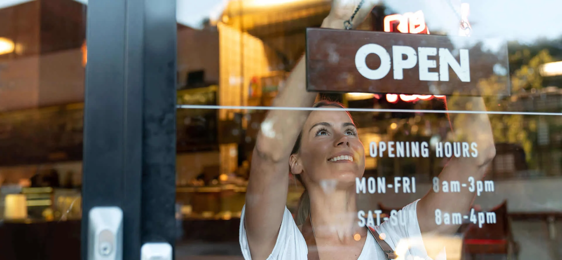 Woman hanging open sign on door