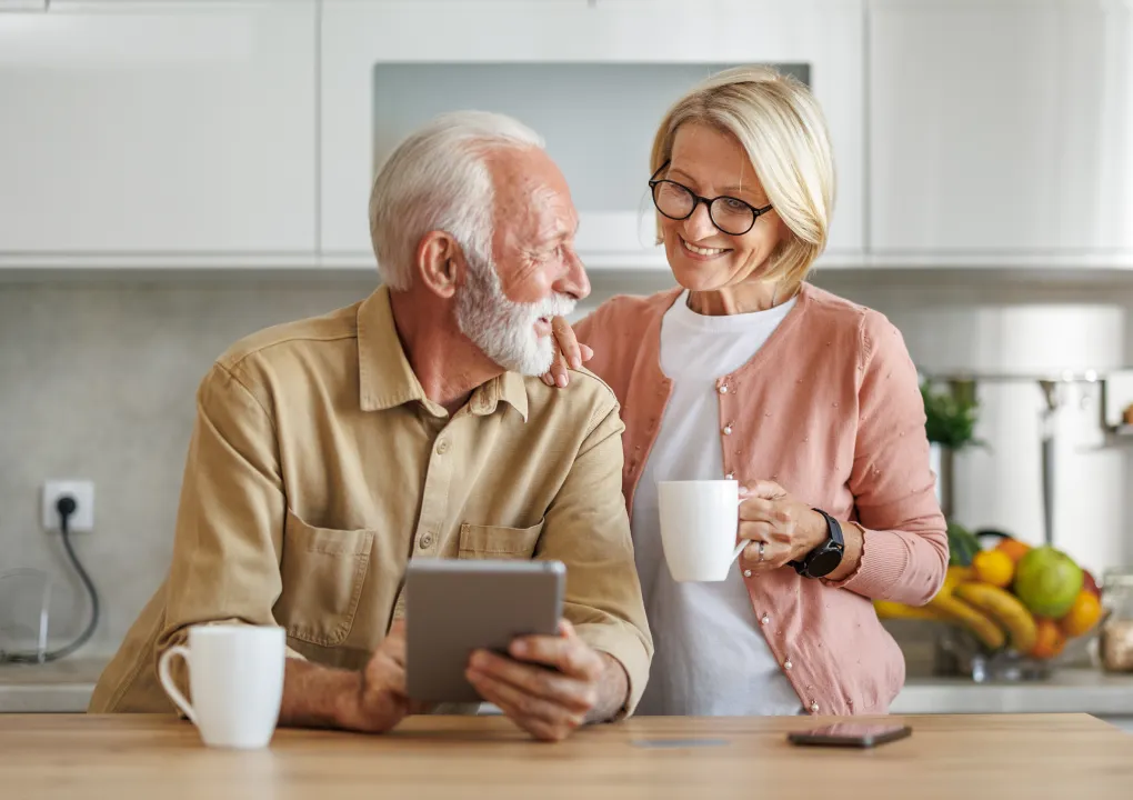Mature couple smiling over coffee in kitchen