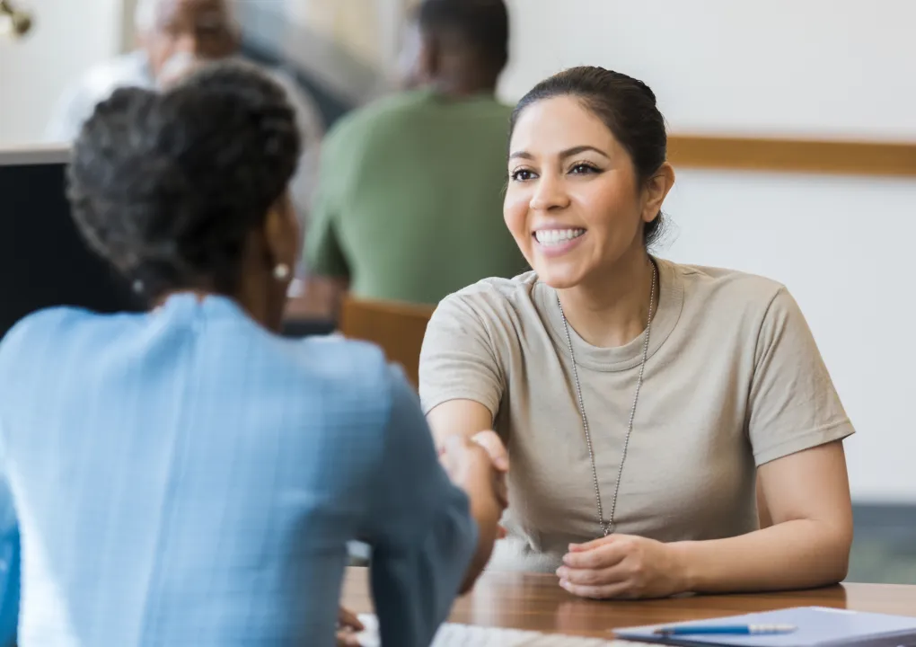 Two ladies shaking hands in a business setting