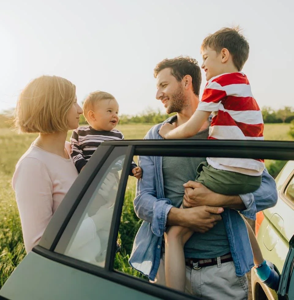 Family standing beside car