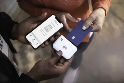 A merchant’s hands hold a mobile phone and Clover Go wireless credit card reader while a customer inserts their chip credit card into the reader