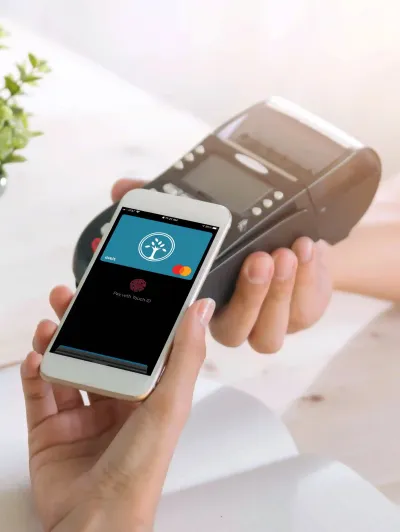 A hand holds a smart phone up to a card reader to use mobile pay with a Southern Bank Mastercard® Debit Card