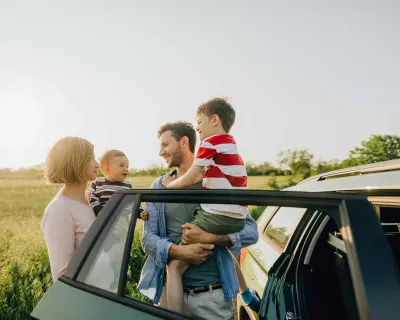 Family standing beside car