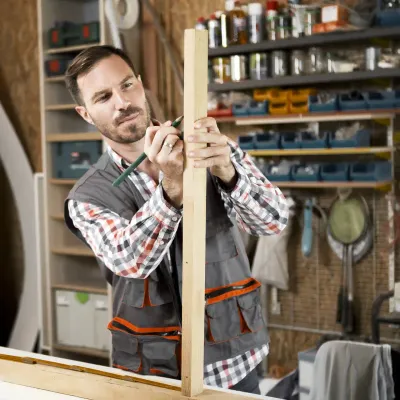 Man in shop measuring a board