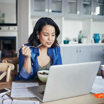 Woman eating lunch while working on computer