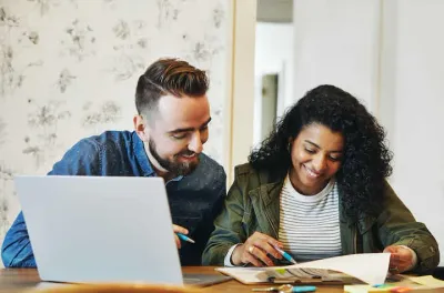 A young couple uses their computer to research a home loan.